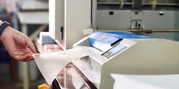 seseorang sedang menggunakan mesin laminating